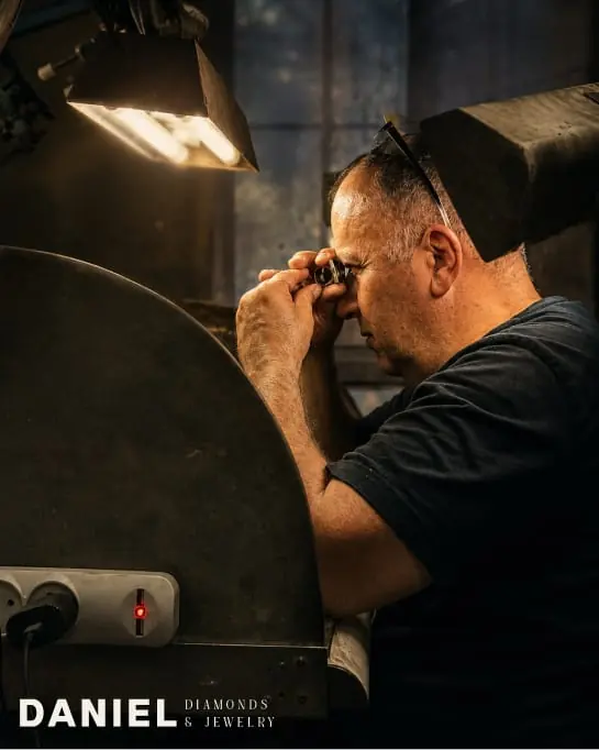 A jeweller at the bench under a lamp, for Daniel Diamonds & Jewelry