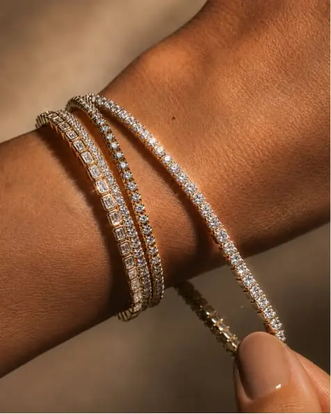 A wrist wearing two diamond tennis bracelets
