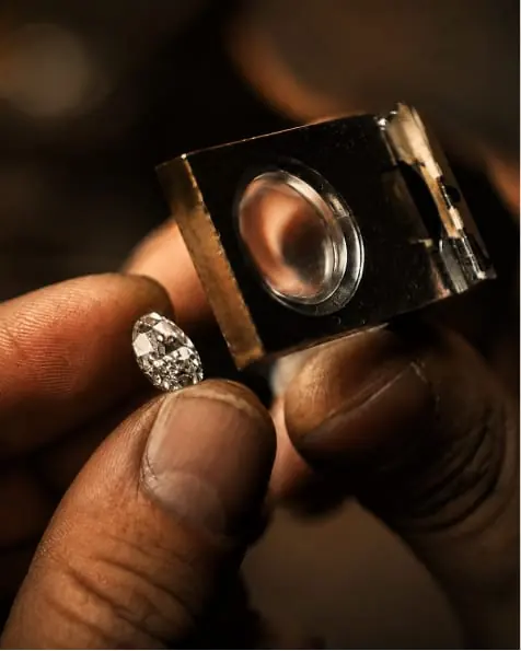 A diamond ring held in a jeweller's loupe