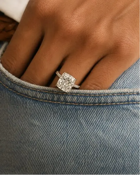Diamond solitaire ring on a hand in a denim pocket