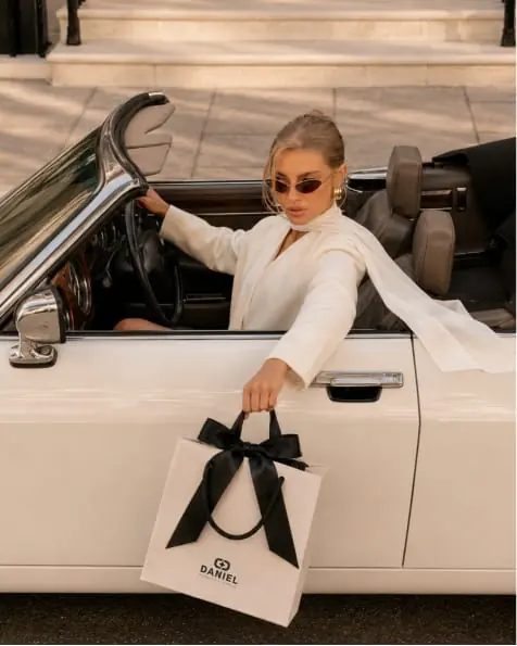 A woman stepping out of a white convertible with a Daniel bag