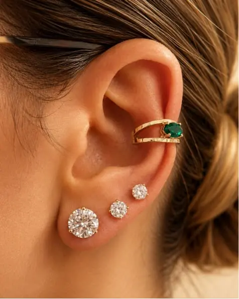 Close-up of an ear with a gold cuff and diamond studs
