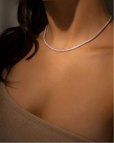 A diamond tennis necklace at the collarbone