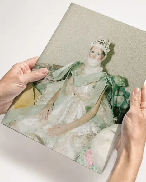 Hands holding a printed page of a figure in green silk